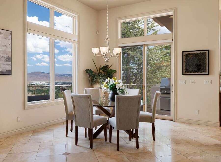 Experience breathtaking panoramic views from this elegant dining room, featuring a glass-top dining table with upholstered chairs.