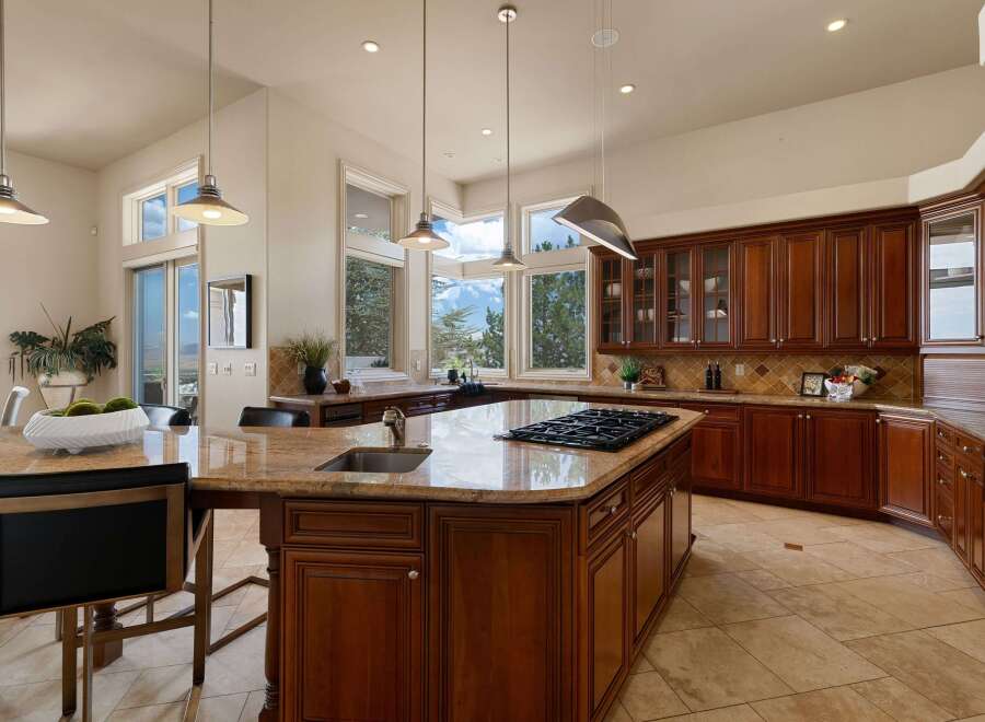 Experience luxury in this spacious kitchen featuring rich cherry wood cabinetry and a large granite island with a built-in gas range.