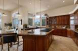 Experience luxury in this spacious kitchen featuring rich cherry wood cabinetry and a large granite island with a built-in gas range.