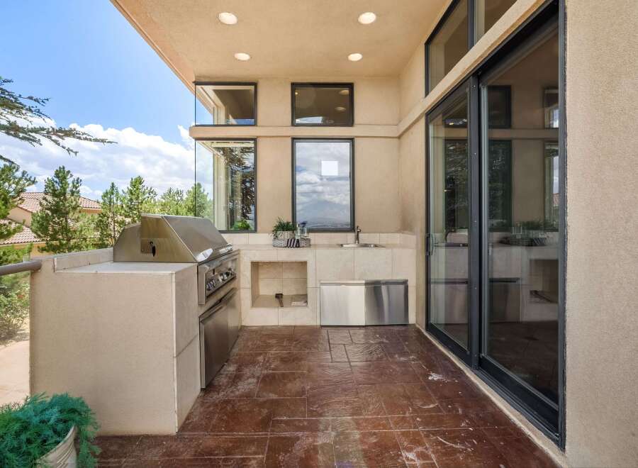 Experience outdoor living at its finest with this well-appointed patio kitchen, featuring a built-in stainless steel grill and a convenient sink area.