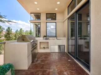 Experience outdoor living at its finest with this well-appointed patio kitchen, featuring a built-in stainless steel grill and a convenient sink area.