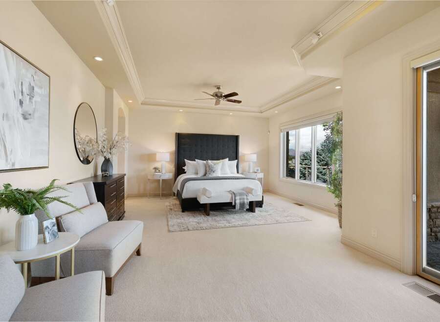 Experience luxurious living in this spacious master suite, featuring a king-size bed with a dramatic upholstered headboard and plush bedding.