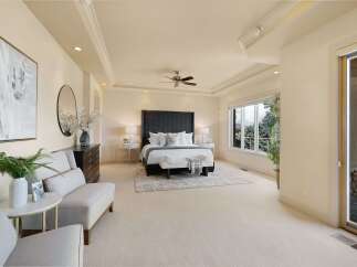 Experience luxurious living in this spacious master suite, featuring a king-size bed with a dramatic upholstered headboard and plush bedding.