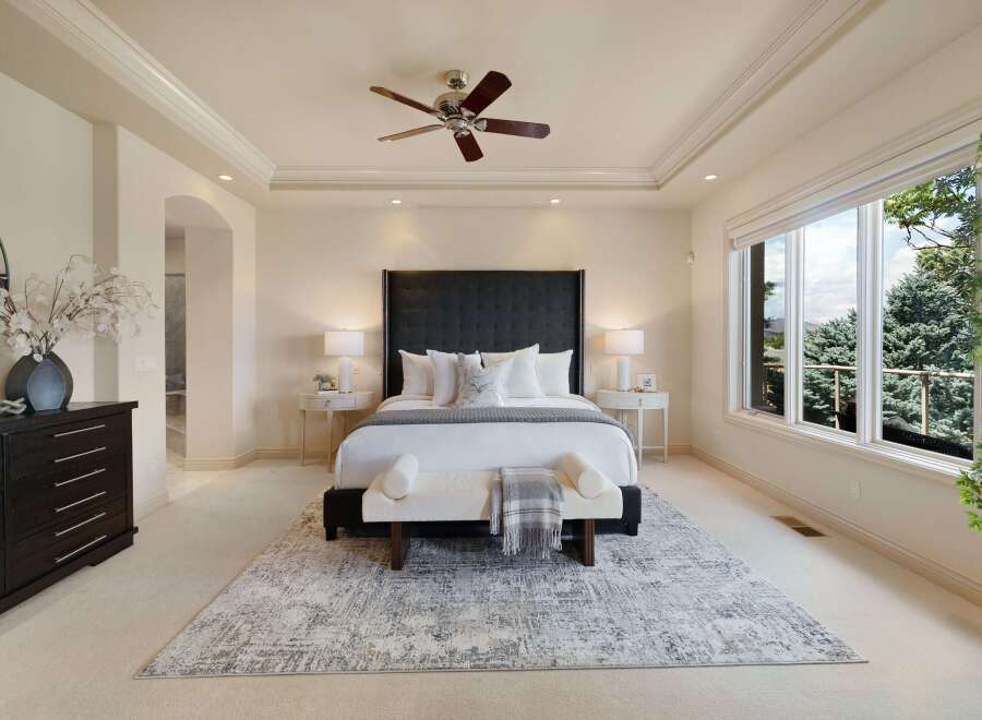 Experience luxury in this master suite, featuring a king-size bed with a tufted headboard and plush white bedding.