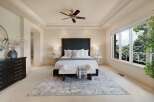 Experience luxury in this master suite, featuring a king-size bed with a tufted headboard and plush white bedding.