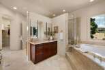 Indulge in luxury in this spacious master bathroom, featuring a large soaking tub with a marble surround and a separate glass-enclosed shower.