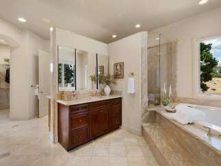 Indulge in luxury in this spacious master bathroom, featuring a large soaking tub with a marble surround and a separate glass-enclosed shower.