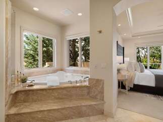 Indulge in luxury with this spacious master suite featuring a spa-like bathroom with a large soaking tub and stunning nature views.