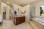 This luxurious bathroom features a spacious vanity with a marble countertop and dark wood cabinetry, complemented by a large mirror with integrated lighting.