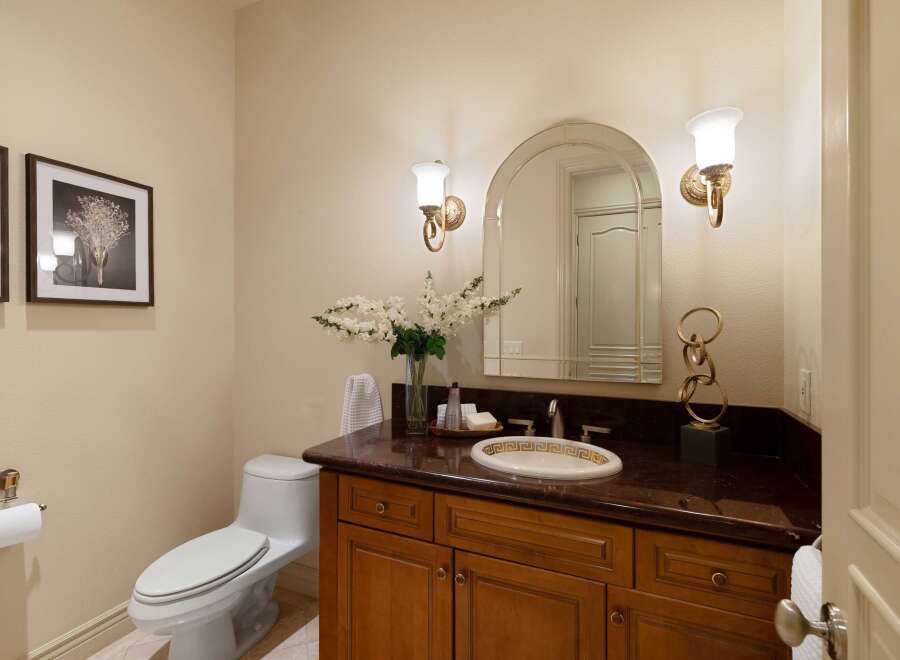 This elegant bathroom features a sleek white toilet and a stylish vanity with a dark granite countertop.