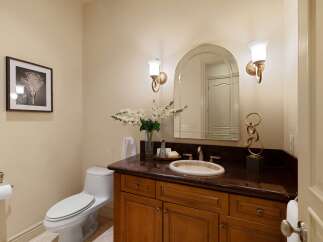 This elegant bathroom features a sleek white toilet and a stylish vanity with a dark granite countertop.