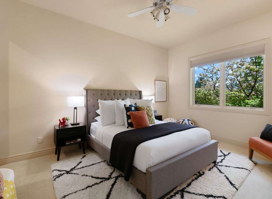 This inviting bedroom features a plush king-sized bed with a tufted headboard, complemented by a dark charcoal quilt and an assortment of decorative pillows.