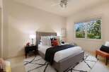 This inviting bedroom features a plush king-sized bed with a tufted headboard, complemented by a dark charcoal quilt and an assortment of decorative pillows.