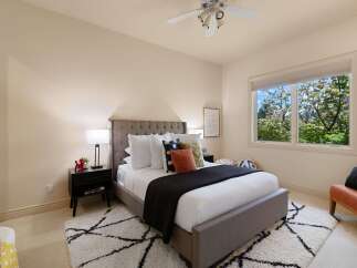 This inviting bedroom features a plush king-sized bed with a tufted headboard, complemented by a dark charcoal quilt and an assortment of decorative pillows.