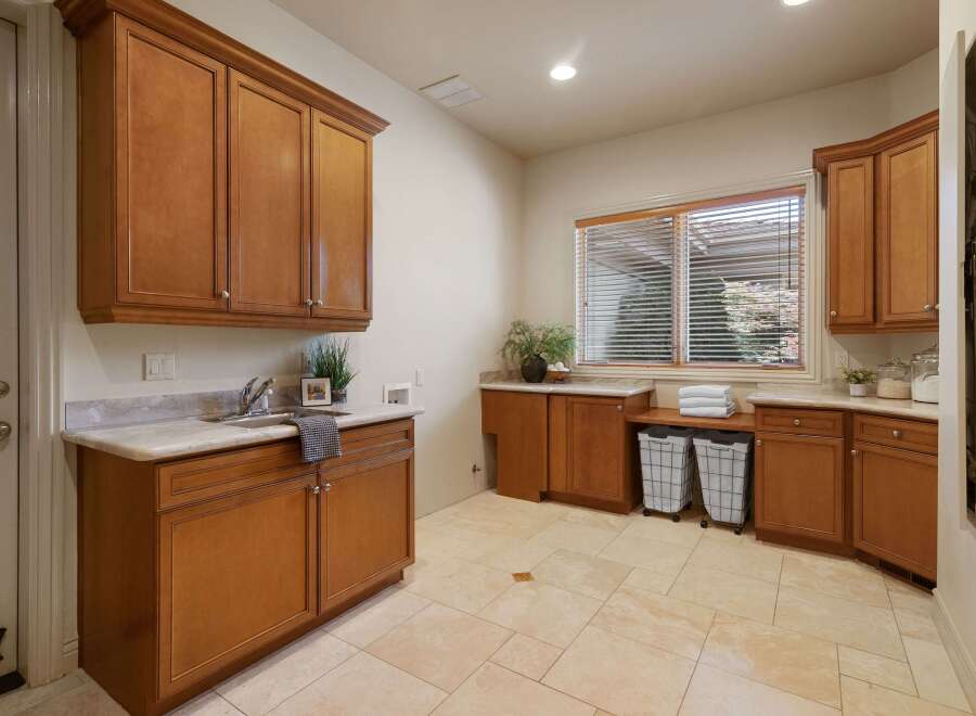 This spacious laundry room features beautiful custom wood cabinetry, providing ample storage for all your laundry needs.
