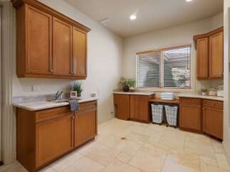 This spacious laundry room features beautiful custom wood cabinetry, providing ample storage for all your laundry needs.