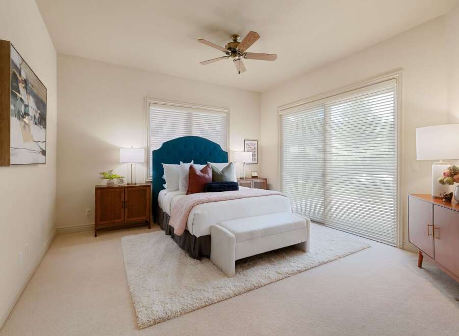 This inviting bedroom features a plush teal tufted headboard, complemented by a soft pink throw and a cozy white bench at the foot of the bed.