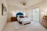 This inviting bedroom features a plush teal tufted headboard, complemented by a soft pink throw and a cozy white bench at the foot of the bed.