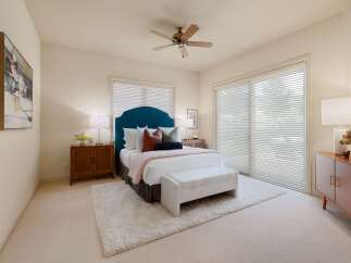 This inviting bedroom features a plush teal tufted headboard, complemented by a soft pink throw and a cozy white bench at the foot of the bed.