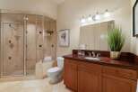 This elegant bathroom features a spacious glass-enclosed shower with travertine tile and a built-in shelf.