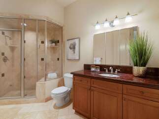 This elegant bathroom features a spacious glass-enclosed shower with travertine tile and a built-in shelf.