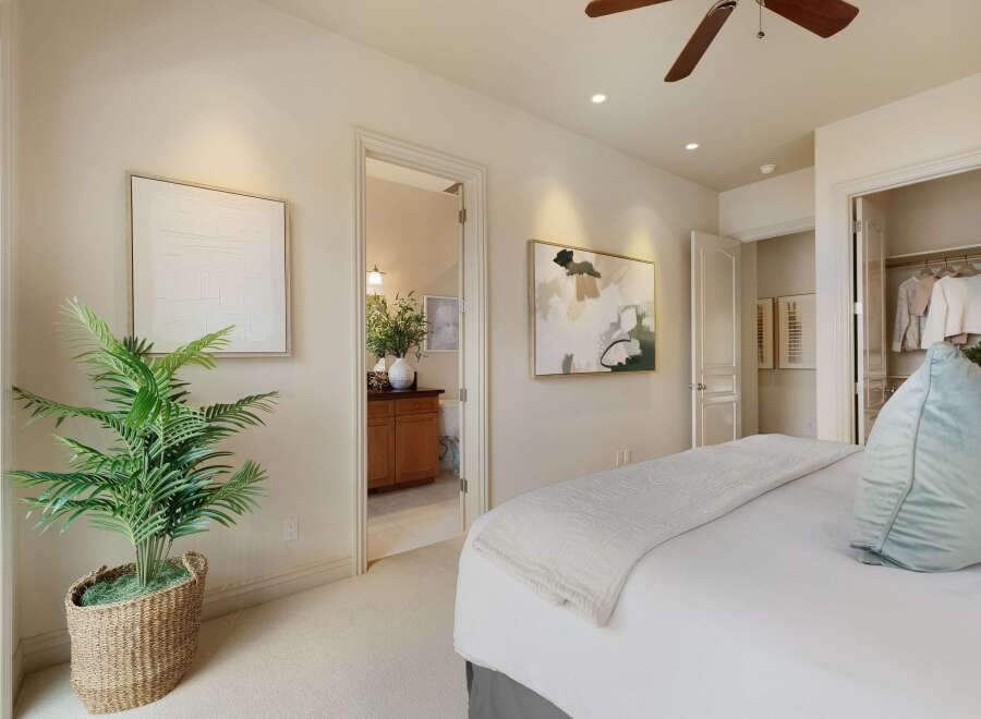 This bedroom offers a serene retreat with a plush bed adorned with a light-colored quilt and a soft blue accent pillow.
