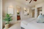 This bedroom offers a serene retreat with a plush bed adorned with a light-colored quilt and a soft blue accent pillow.