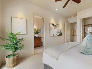 This bedroom offers a serene retreat with a plush bed adorned with a light-colored quilt and a soft blue accent pillow.