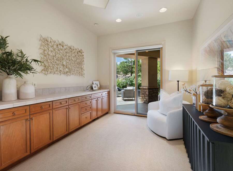 This spacious room features a long, built-in wooden cabinet with ample storage and a tiled countertop, perfect for a home office or craft area.