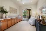This spacious room features a long, built-in wooden cabinet with ample storage and a tiled countertop, perfect for a home office or craft area.