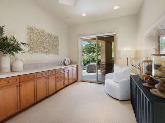 This spacious room features a long, built-in wooden cabinet with ample storage and a tiled countertop, perfect for a home office or craft area.