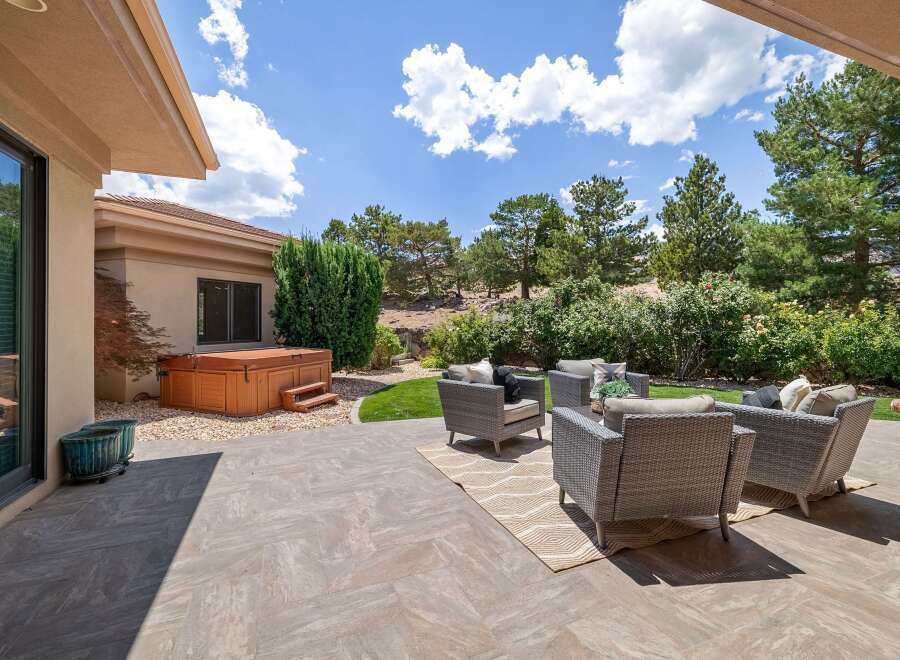 Enjoy outdoor living with this spacious patio featuring a luxurious hot tub and comfortable wicker seating.