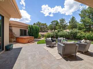 Enjoy outdoor living with this spacious patio featuring a luxurious hot tub and comfortable wicker seating.