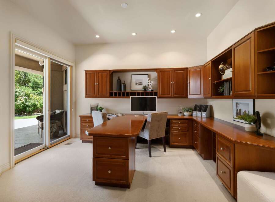 This spacious home office features custom cherry wood cabinetry providing ample storage and a sophisticated aesthetic.