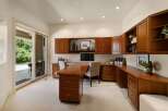 This spacious home office features custom cherry wood cabinetry providing ample storage and a sophisticated aesthetic.
