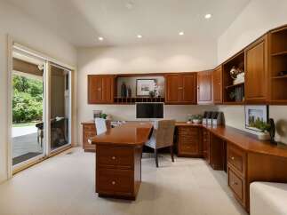 This spacious home office features custom cherry wood cabinetry providing ample storage and a sophisticated aesthetic.