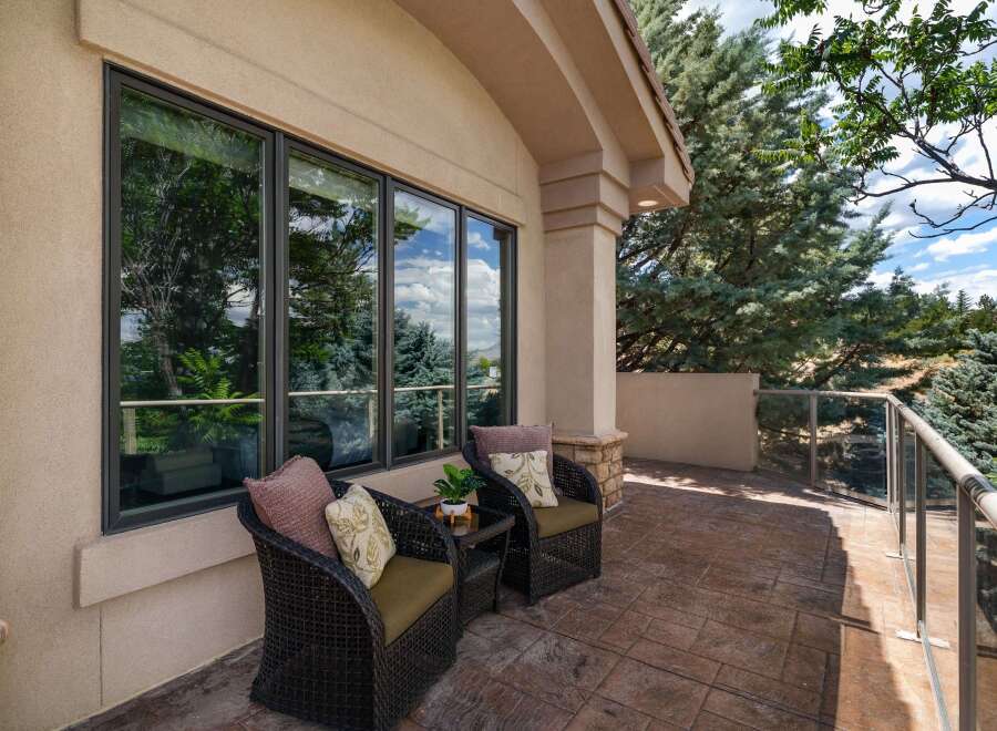 Enjoy the outdoors from this charming patio, featuring two comfortable wicker chairs with decorative pillows and a small side table.