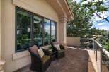 Enjoy the outdoors from this charming patio, featuring two comfortable wicker chairs with decorative pillows and a small side table.