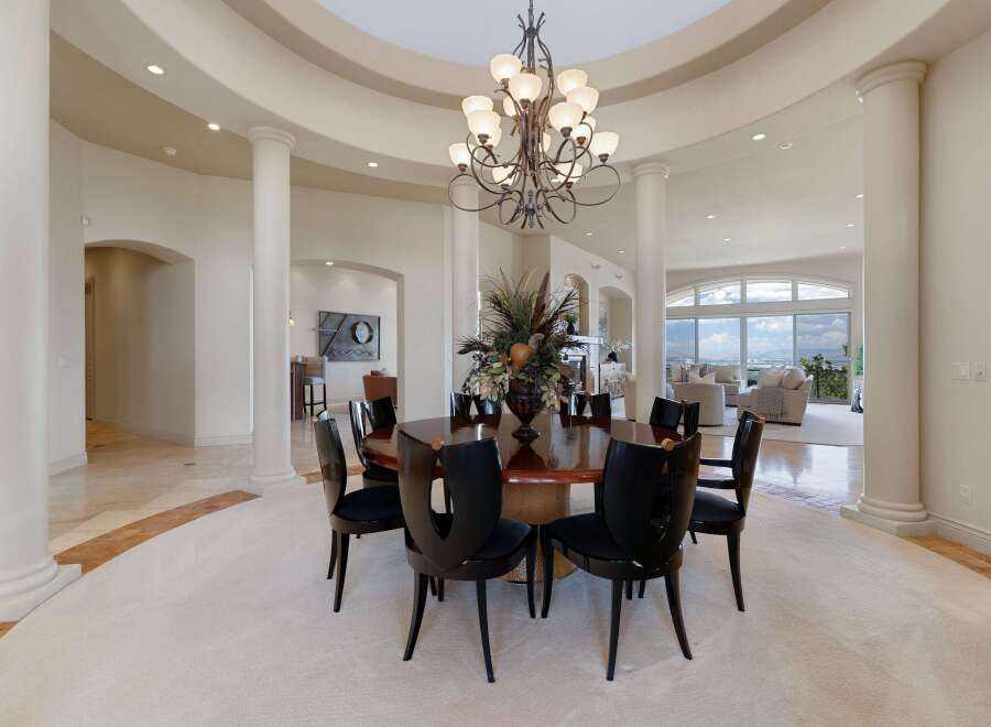 Experience elegant dining in this spacious room, featuring a large, polished wood table surrounded by sleek black chairs.