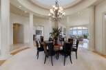 Experience elegant dining in this spacious room, featuring a large, polished wood table surrounded by sleek black chairs.