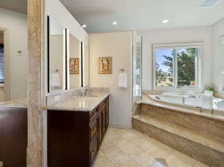 Indulge in luxury with this stunning master bathroom featuring a spacious soaking tub and a large vanity with ample counter space.