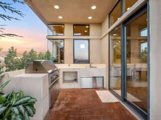 Experience outdoor living at its finest with this modern patio featuring a built-in stainless steel grill and a convenient sink area.