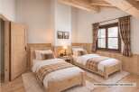 Experience cozy mountain living in this charming bedroom featuring two twin beds with rustic wooden frames and plaid accents.