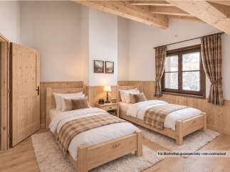 Experience cozy mountain living in this charming bedroom featuring two twin beds with rustic wooden frames and plaid accents.