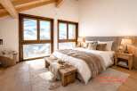 Experience ultimate comfort in this luxurious bedroom, featuring a plush king-size bed adorned with soft, textured throws and pillows.