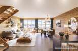 Experience luxury mountain living in this stunning open-concept living space, featuring a modern sectional sofa, a cozy leather ottoman, and a spacious dining area perfect for entertaining.