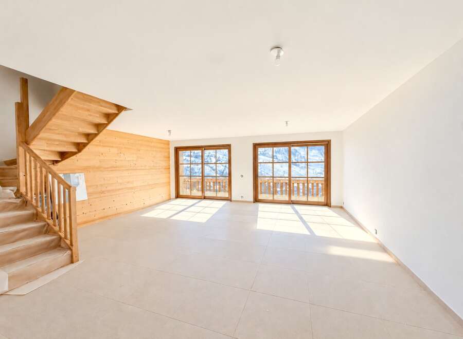 Experience modern living in this spacious, unfinished interior featuring a beautiful wooden staircase and accent wall.
