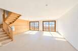 Experience modern living in this spacious, unfinished interior featuring a beautiful wooden staircase and accent wall.