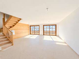 Experience modern living in this spacious, unfinished interior featuring a beautiful wooden staircase and accent wall.