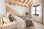 Experience cozy living in this charming bedroom featuring exposed wooden beams and a sloped ceiling, creating a rustic and inviting atmosphere.